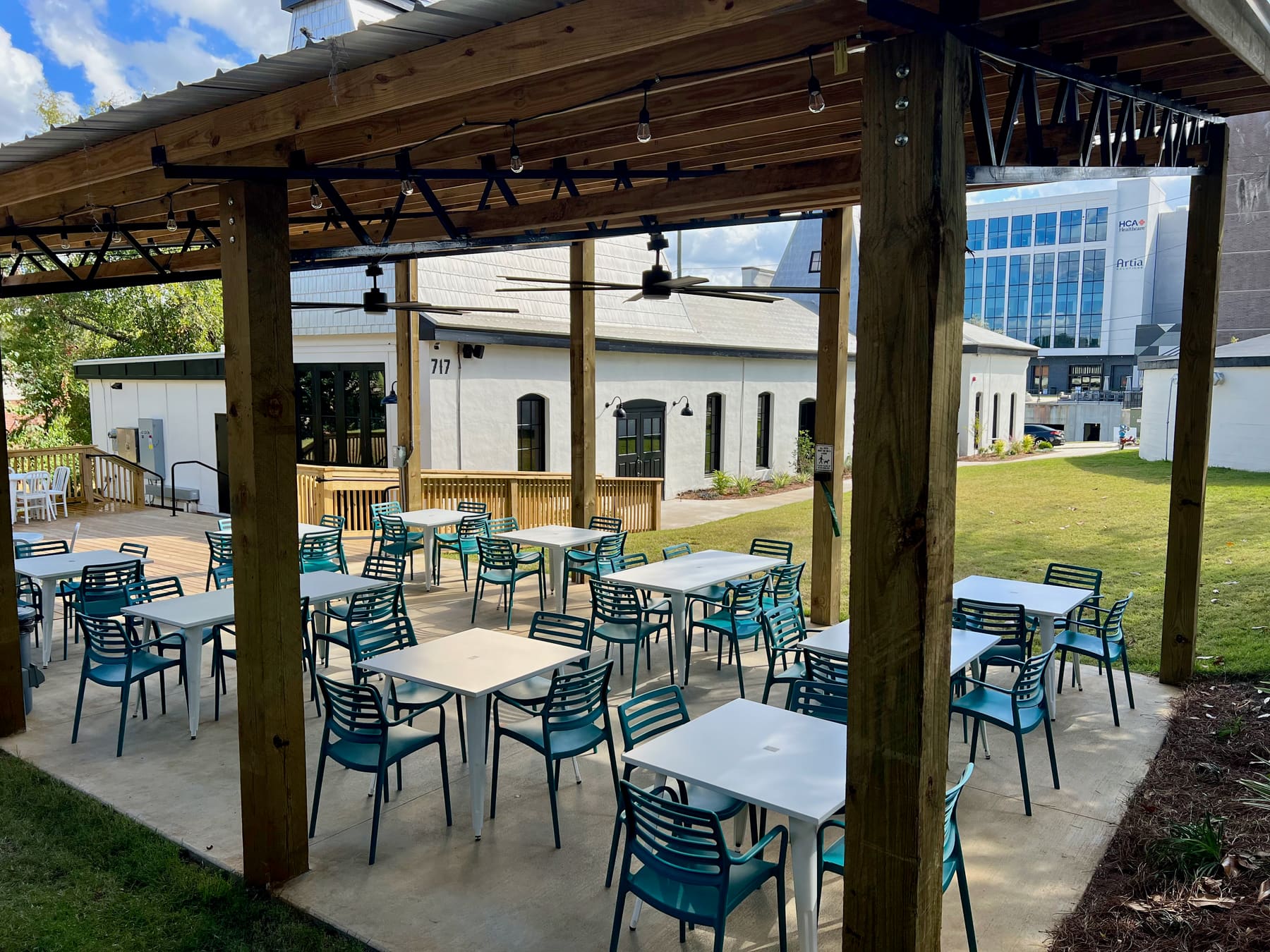 White tables and teal chairs ready under the beer garden pavilion.