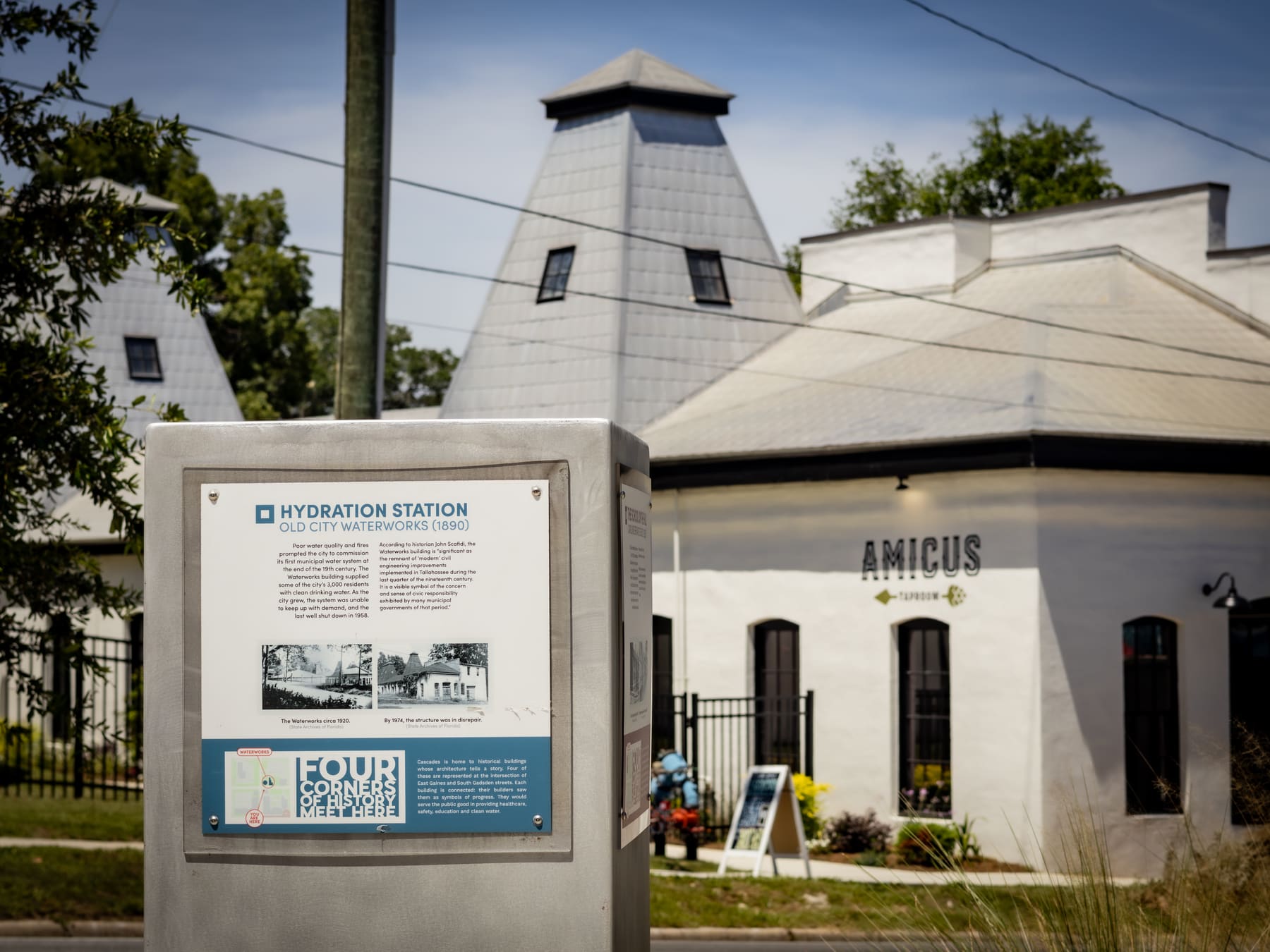 A metal history marker reading Hydration Station, Old City Waterworks 1890, in front of the white building and its pyramid roof.